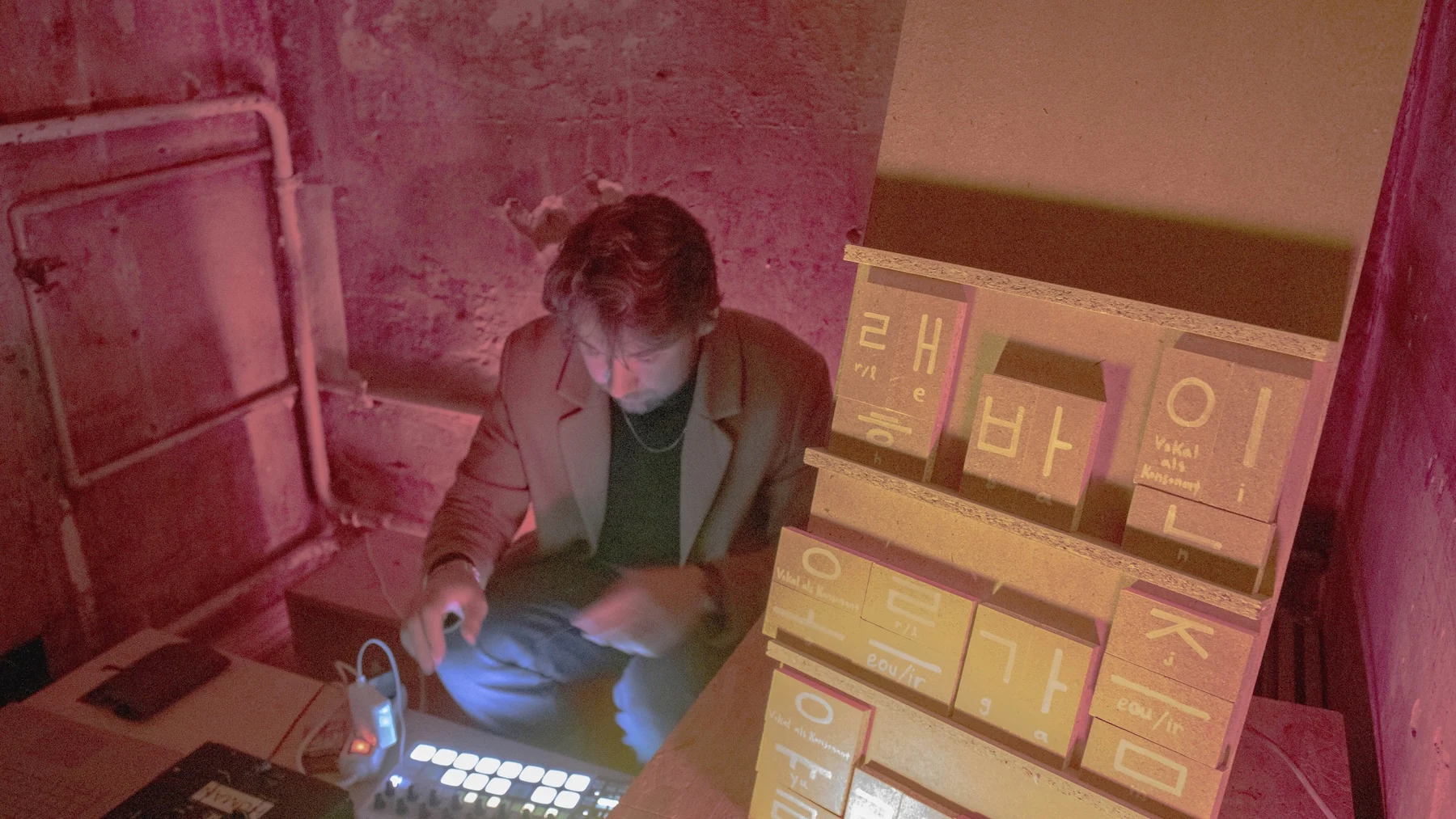 David Knop at his controller behind a shelf of Korean syllables built from wooden blocks