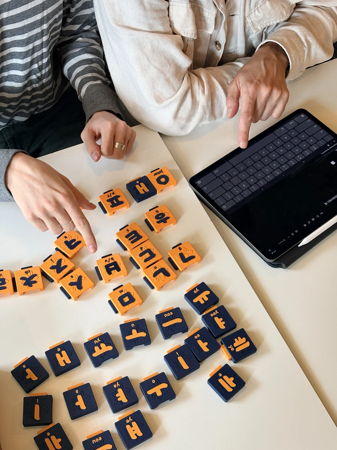 Two people arranging the tiles on a table