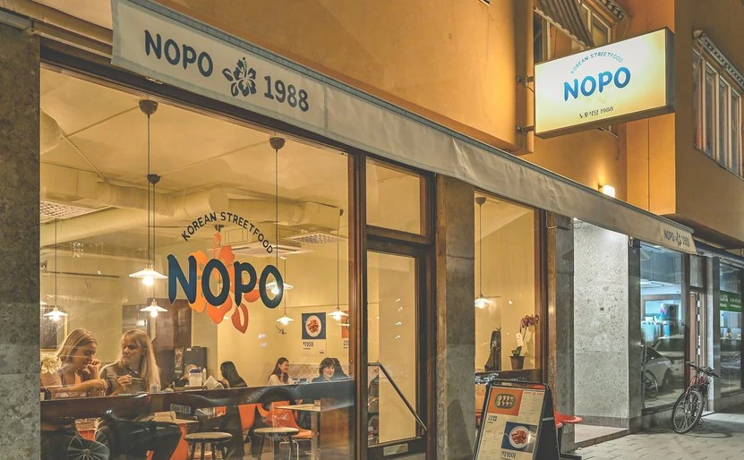 Nopo 1988 seen from the street at night, with its logo in the window